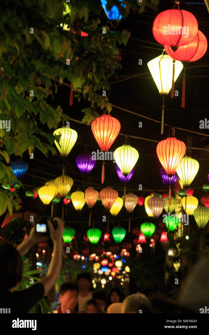 Tourists mix with locals under colourful lanterns in the old town of Hoi An, Vietnam Stock Photo