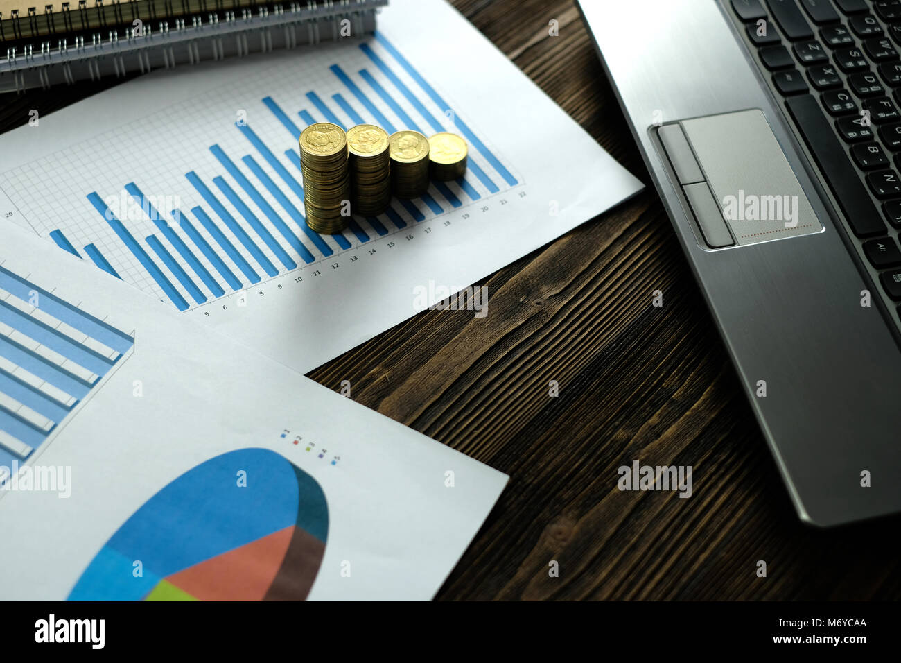 Step of coins stacks with notebook laptop computer and financial graph ...