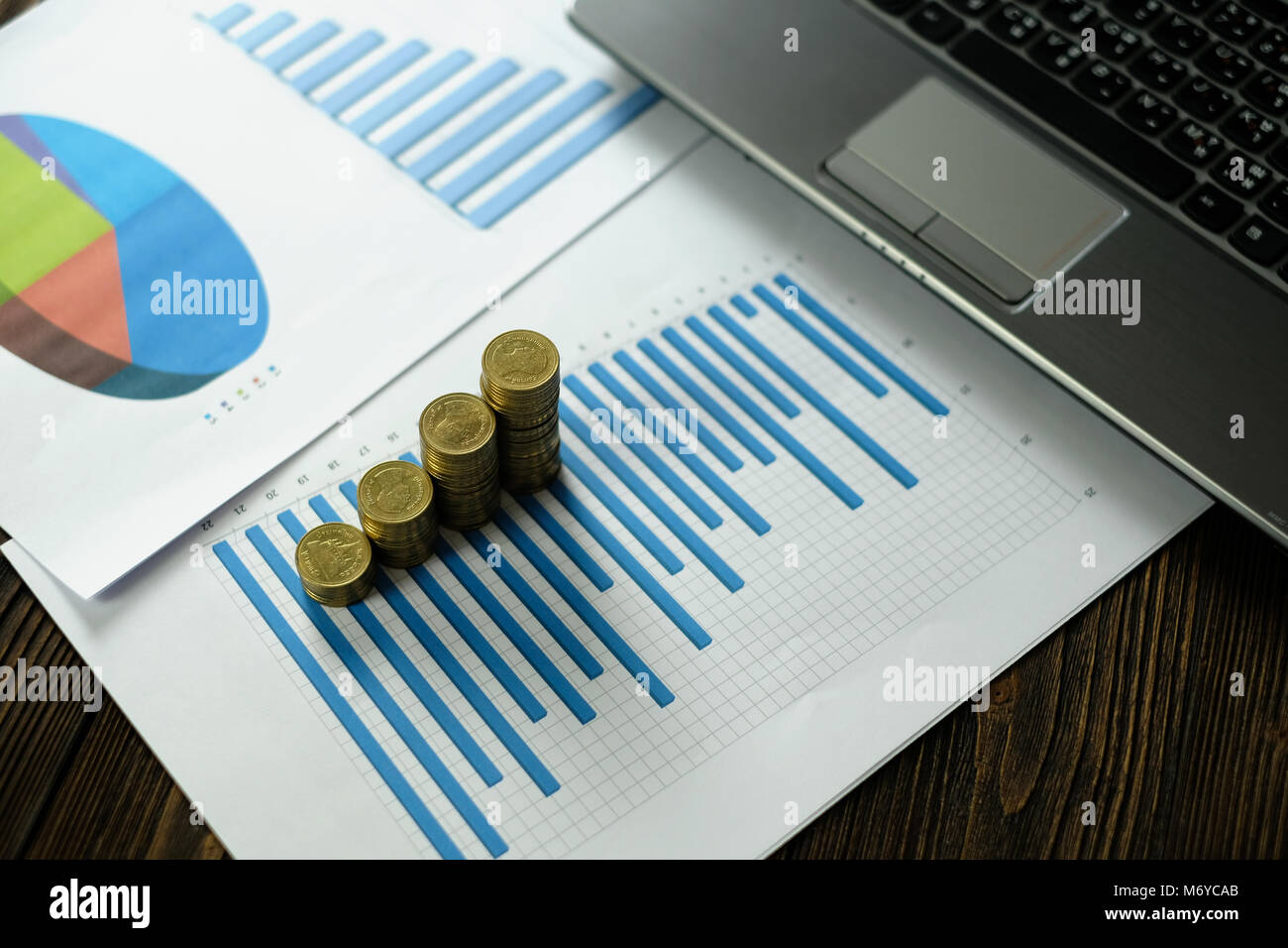 Step of coins stacks with notebook laptop computer and financial graph ...