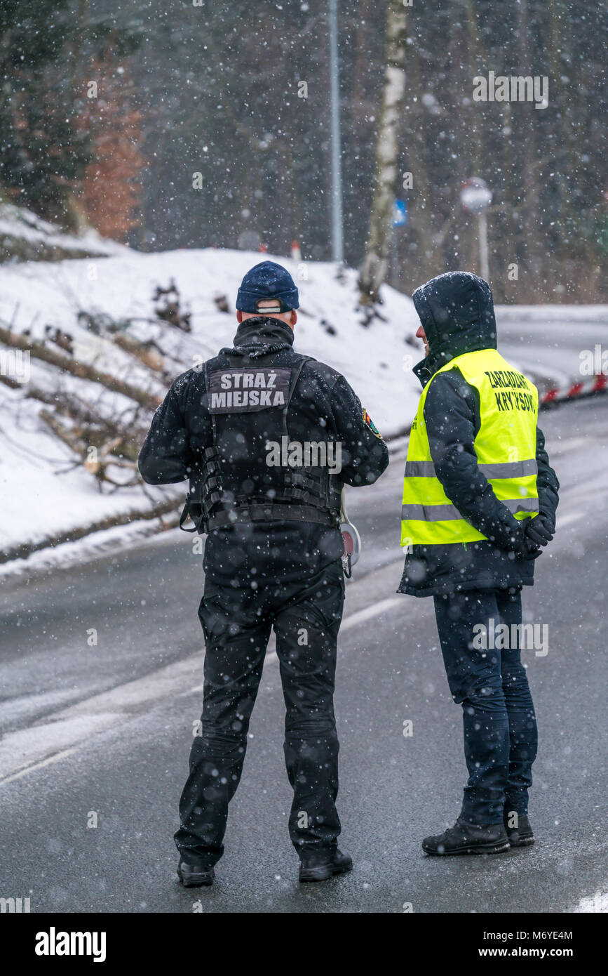Karpacz, Poland -  February 2018 : Policeman and civil guard standing on the road blocking traffic for safety reasons after heavy snowfall Stock Photo