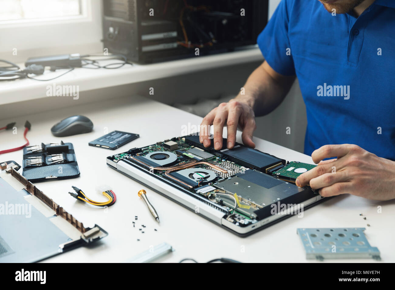 computer repairman installing new hard disk drive in laptop Stock Photo