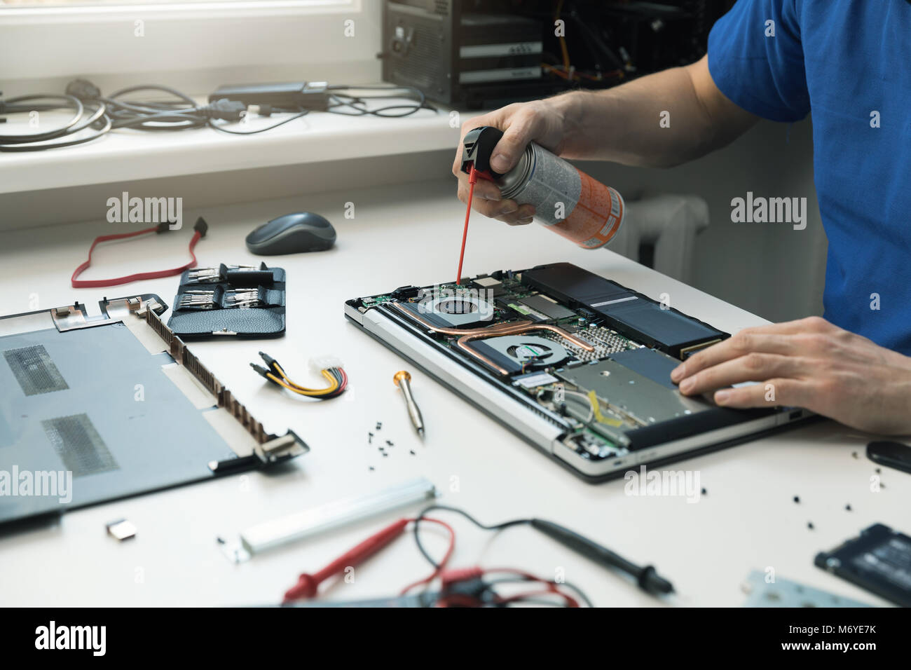 computer maintenance - technician blow out dust from laptop fan Stock Photo