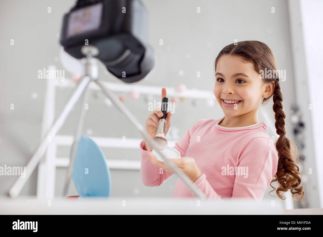 Happy pre-teen girl testing powder for her tutorial Stock Photo