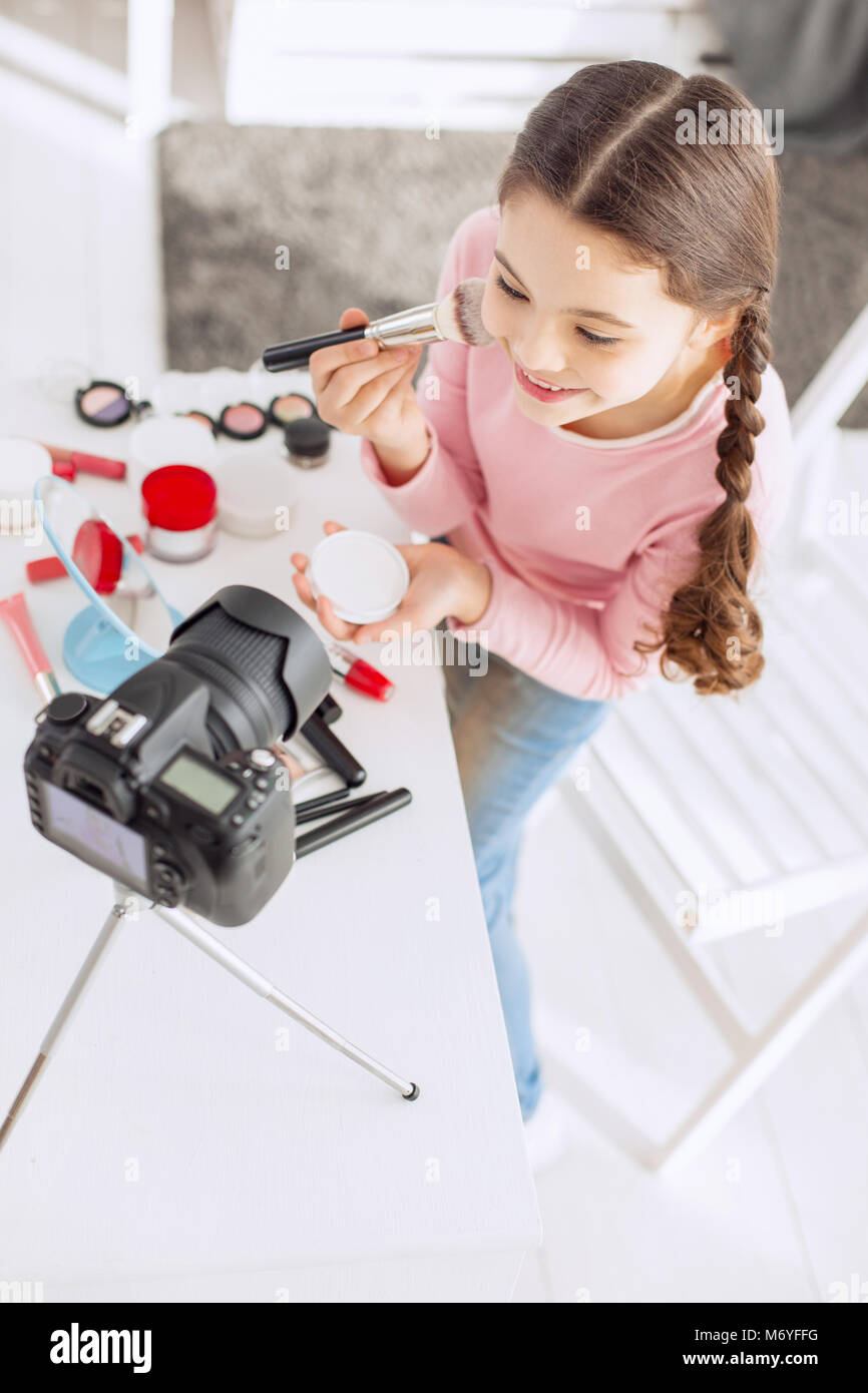 Top view of cheerful girl filming tutorial of applying powder Stock Photo