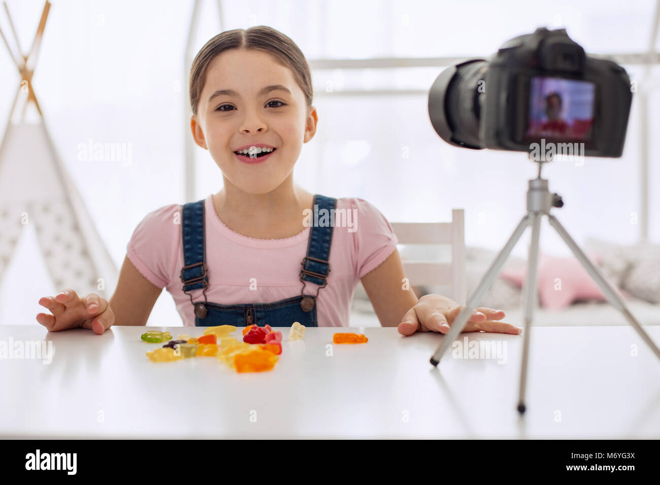 Overjoyed girl posing while eating gummies on camera Stock Photo