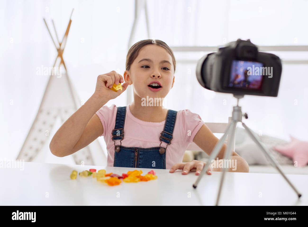 Upbeat girl speaking about taste of gummy candies in vlog Stock Photo