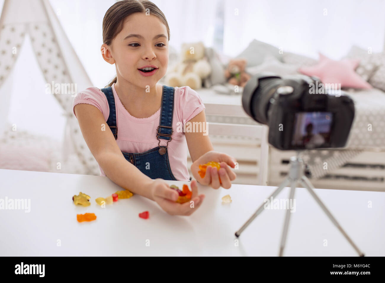 Cheerful girl showing handfuls of gummies to camera Stock Photo