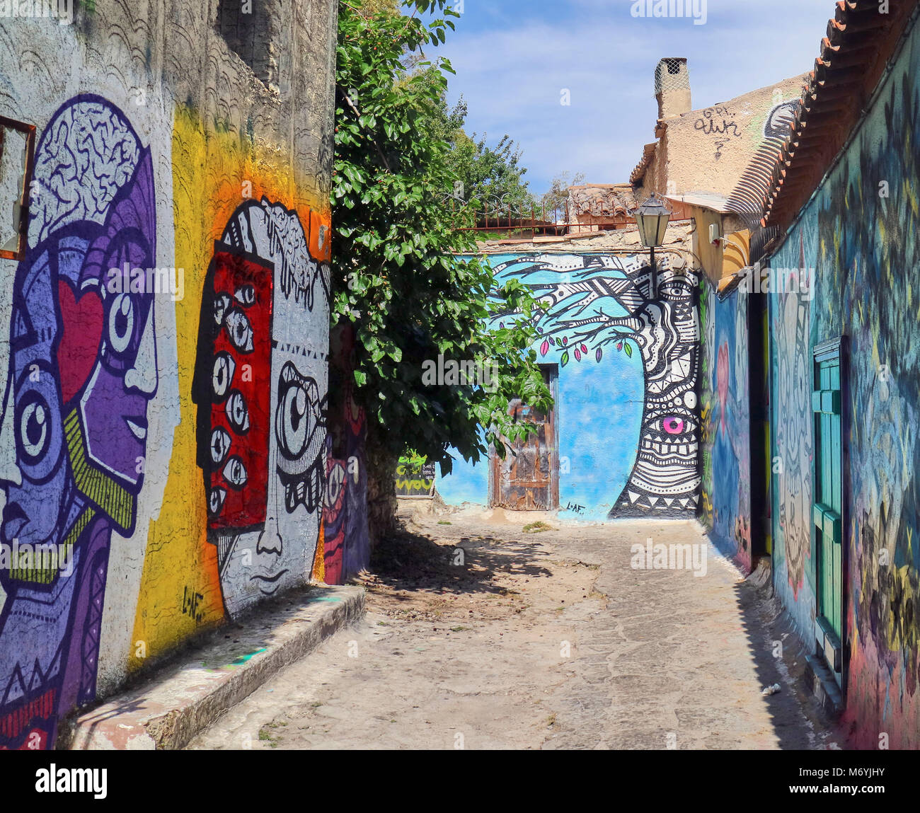 Europe, Greece, Attica Athens,Anafiotika Plaka  ,Graffiti On Wall At Street The part of old town of Athens called Anafiotika is built right below the Acropolis (seen in the background). It resembles the houses of the Greek island of Anafi and it was created by the workers came from that island to help built Athens when it first became the capital of the Greek state. Stock Photo