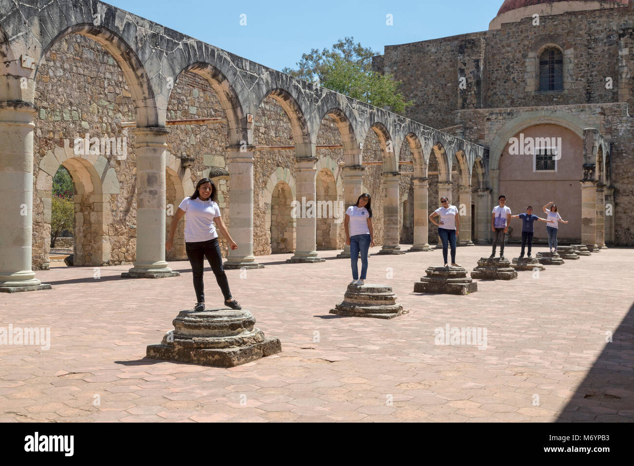 Cuilapam de Guerrero, Oaxaca, Mexico - School children pose on the base of columns in the monastery of Santiago Apóstol. The structure was begun in 15 Stock Photo