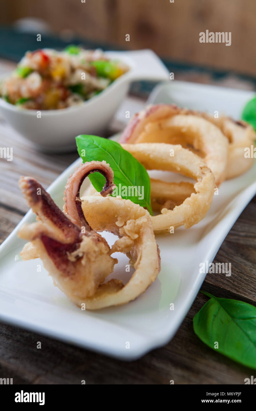 deep fried calamari rings on white tray and salad Stock Photo