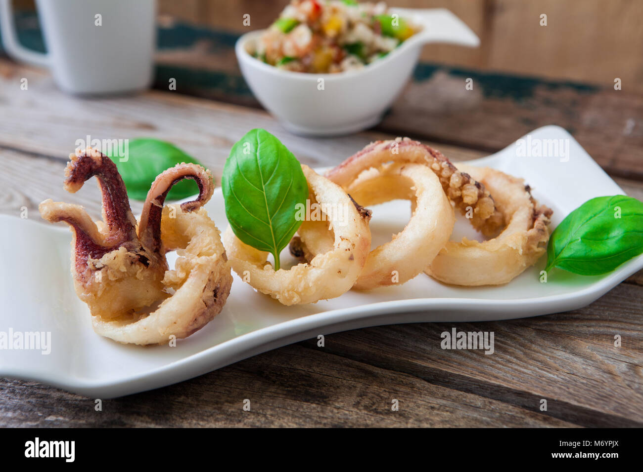 deep fried calamari rings on white tray and salad Stock Photo
