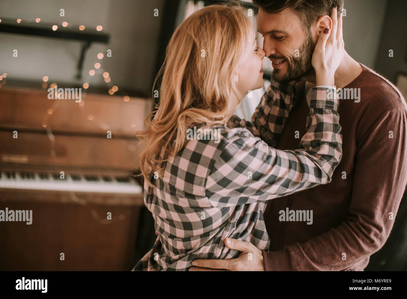 Young man and pregnant woman hugging in the room at home Stock Photo