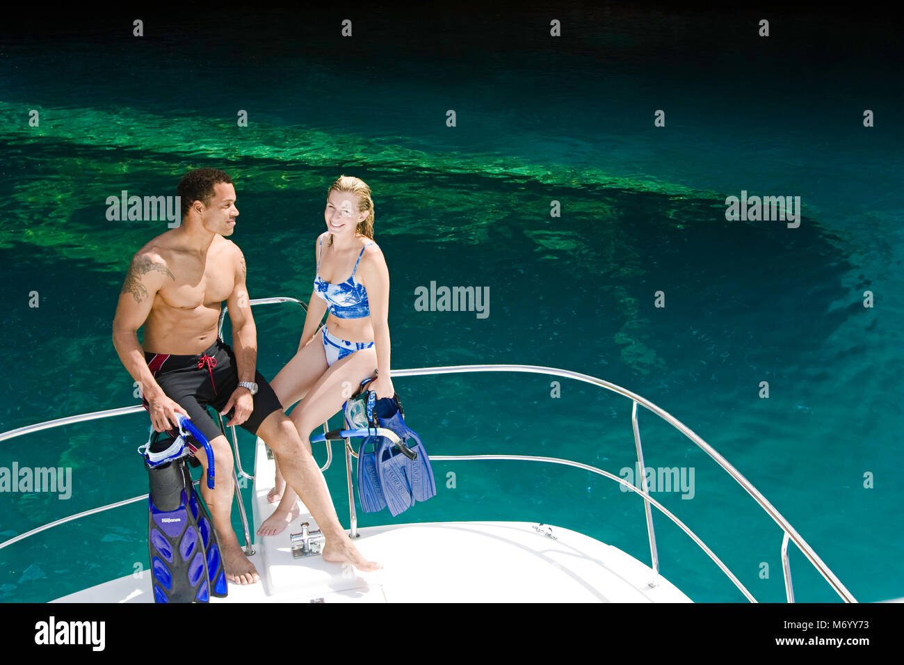 Divers (MR) with snorkel equipment about to enter the water off a boat in The Rock Islands, Palau, Micronesia.  There is a wreck underwater in the bac Stock Photo