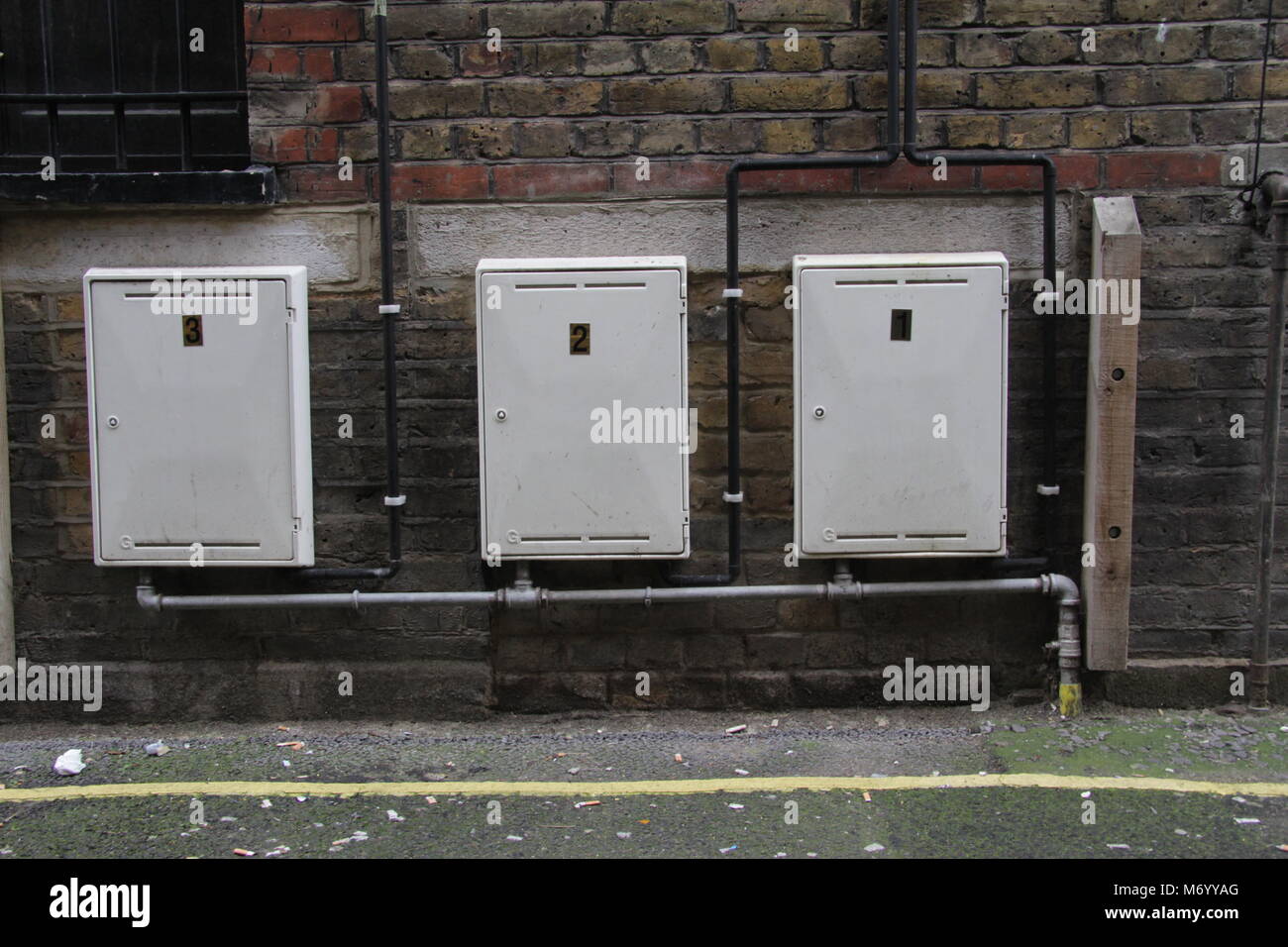 Electrical boxes against brickwall Stock Photo