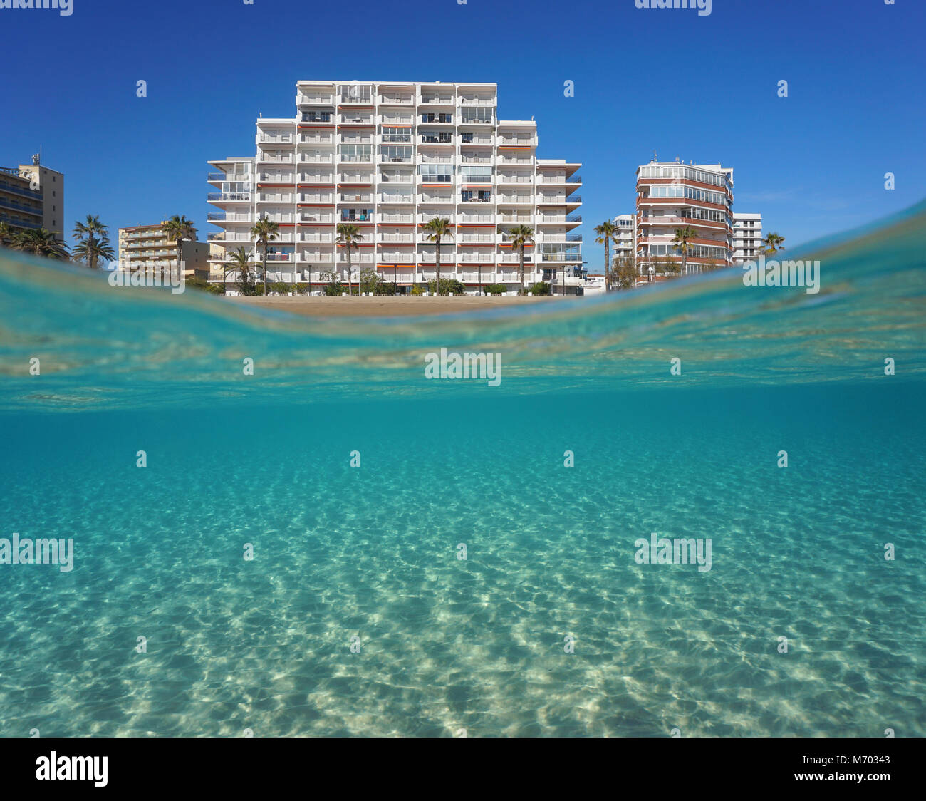 Beachfront apartment building and sandy seabed underwater, split view above and below water surface, Mediterranean sea, Spain, Costa Brava, Catalonia Stock Photo
