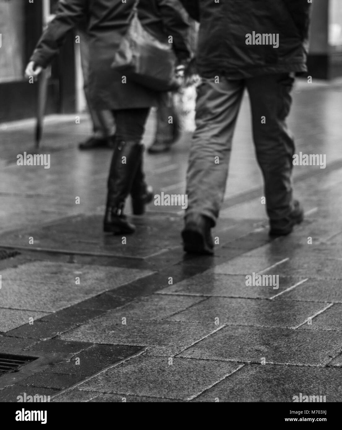 Legs of two people walking down a rainy Street whilst shipping Stock Photo