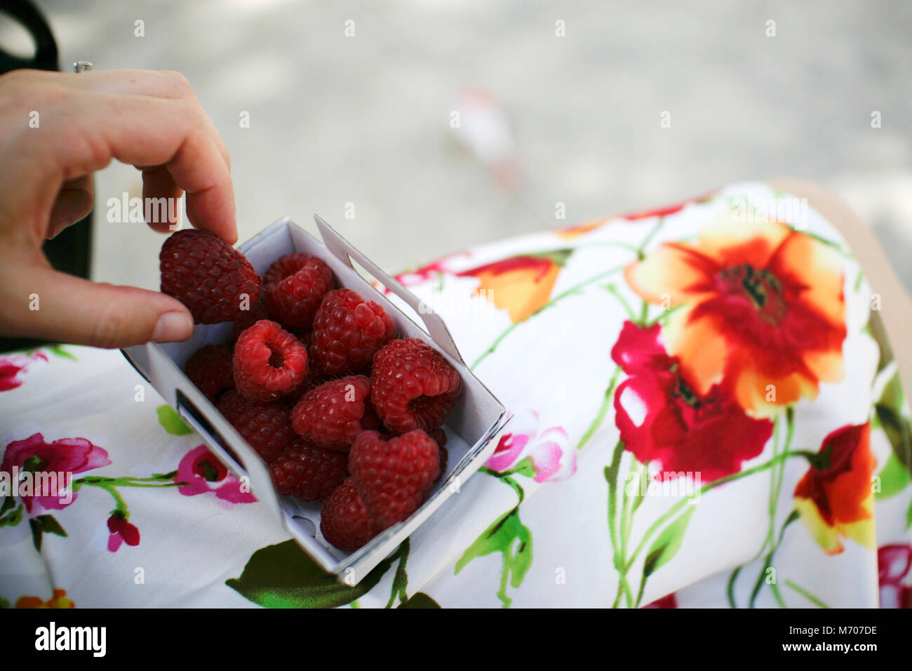 A woman in a red and white dress eats raspberries in the village of Saint Tropez, France. Stock Photo