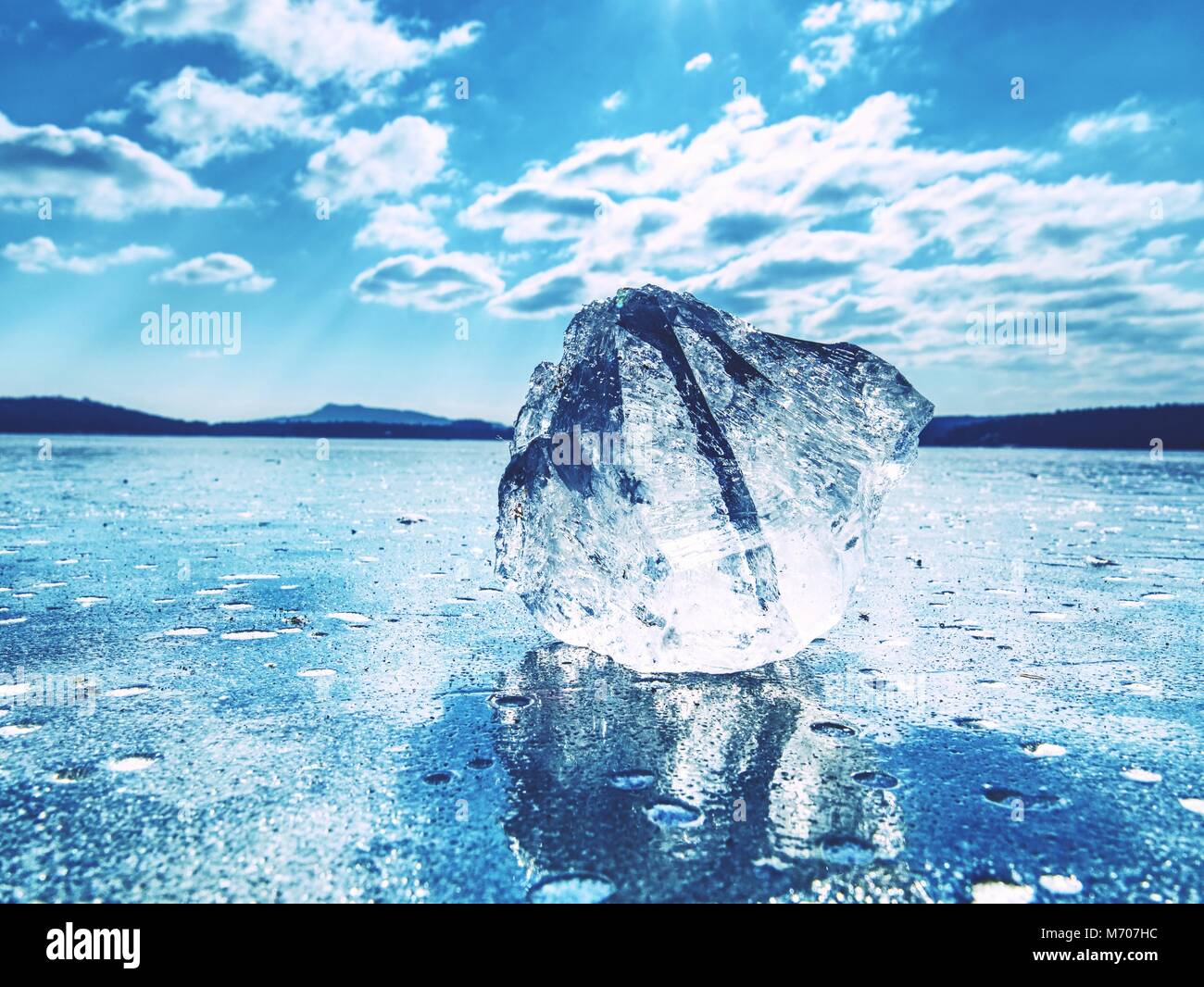 Ice shards on a frozen lake. The rays of the sun creat rainbow shadows in the cracks of the ice. Stock Photo