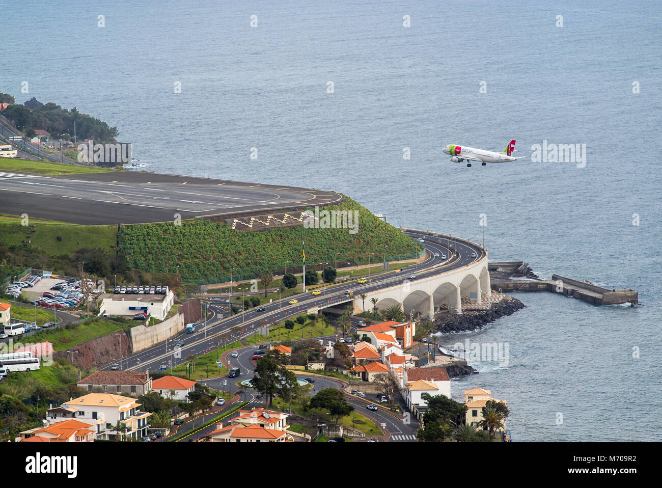 a TAP Portugal aircraft makes the final approach into the infamously challenging Funchal airport approach at Cristiano Ronaldo airport, Madeira Stock Photo