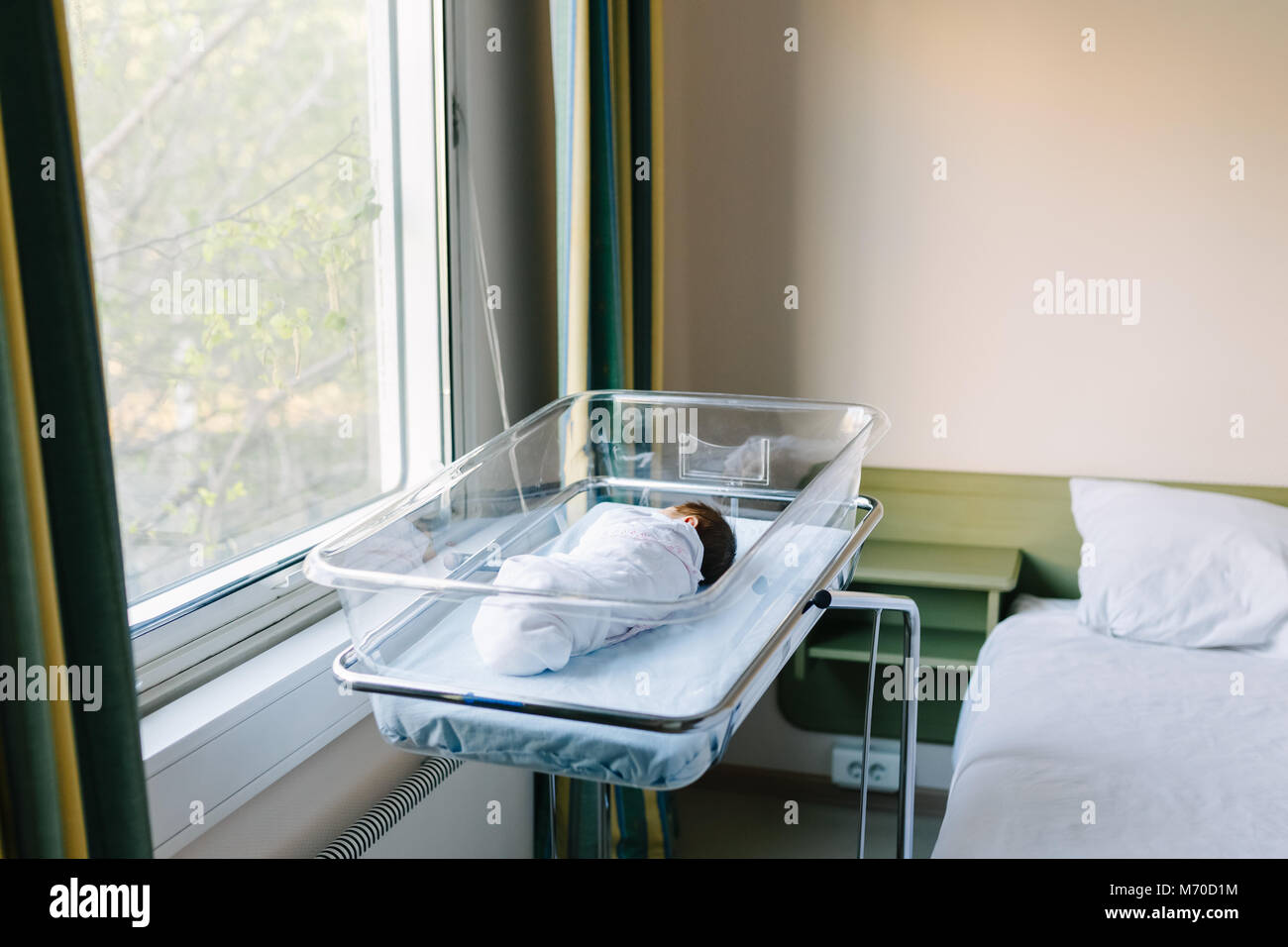 newborn sleeping in bed at the hospital by the window Stock Photo