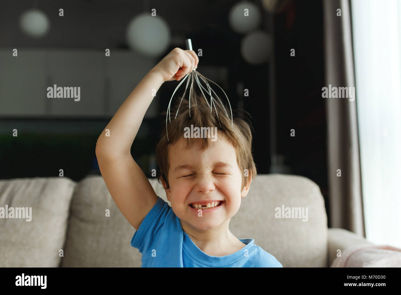 naughty boy having fun with a head massage machine, closing his eyes with  pleasure, smiling without a milk tooth Stock Photo - Alamy