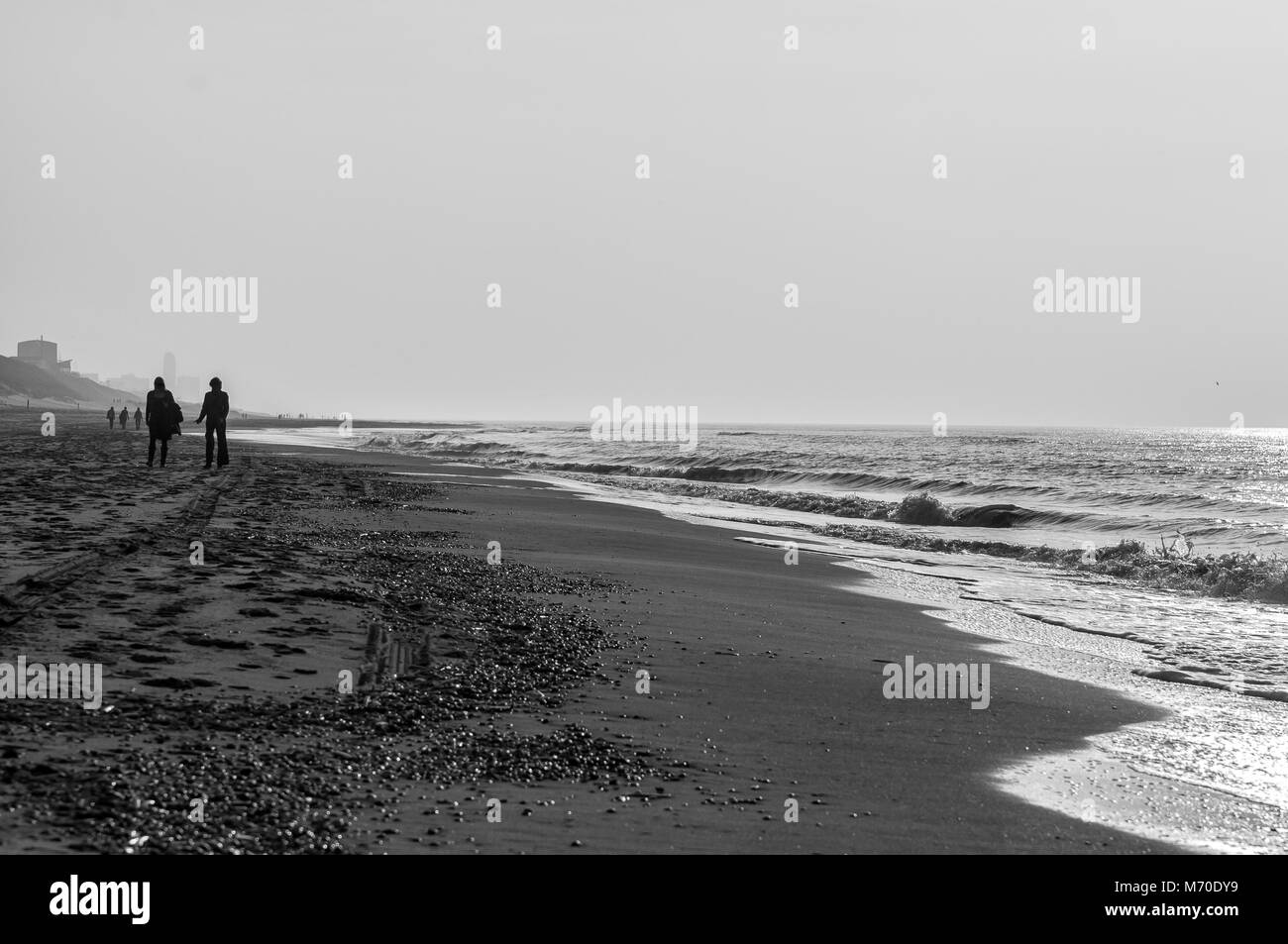 silhouette of two people walking on the beach Stock Photo