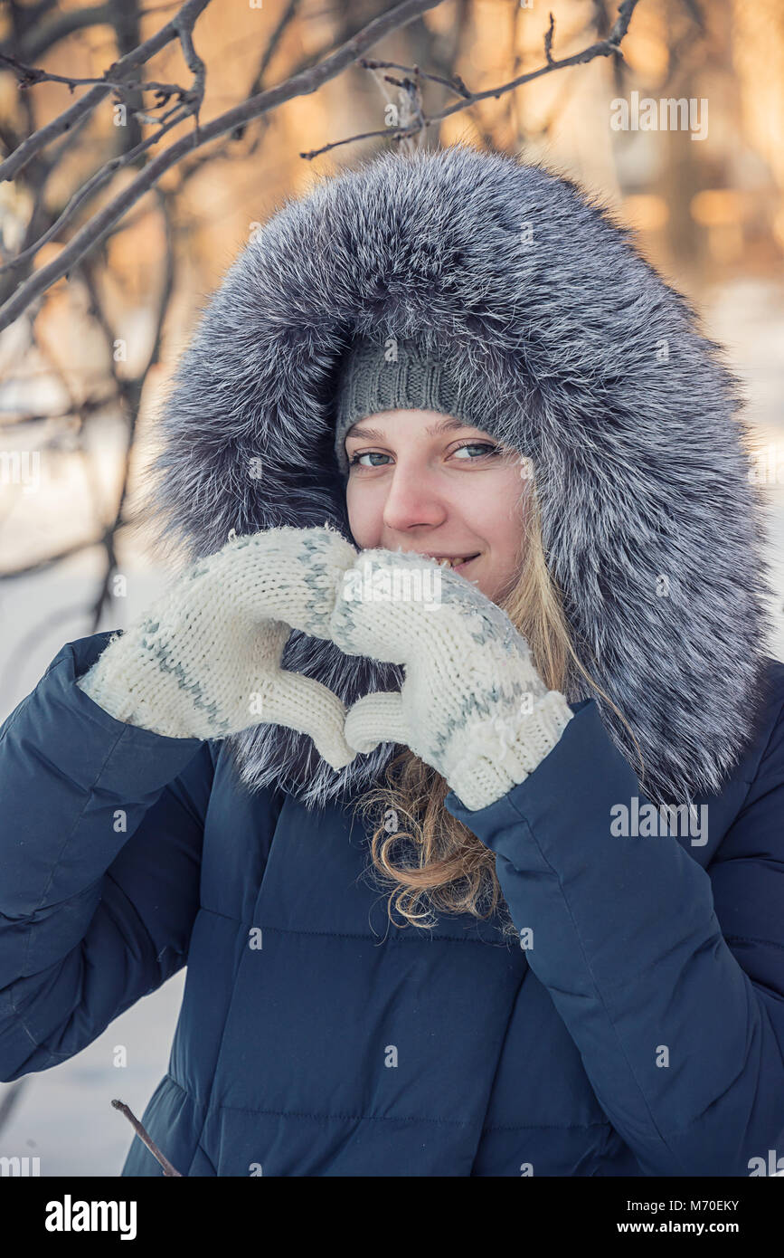 girl in a fur coat shows a heart with your hands, a winter portrait of ...