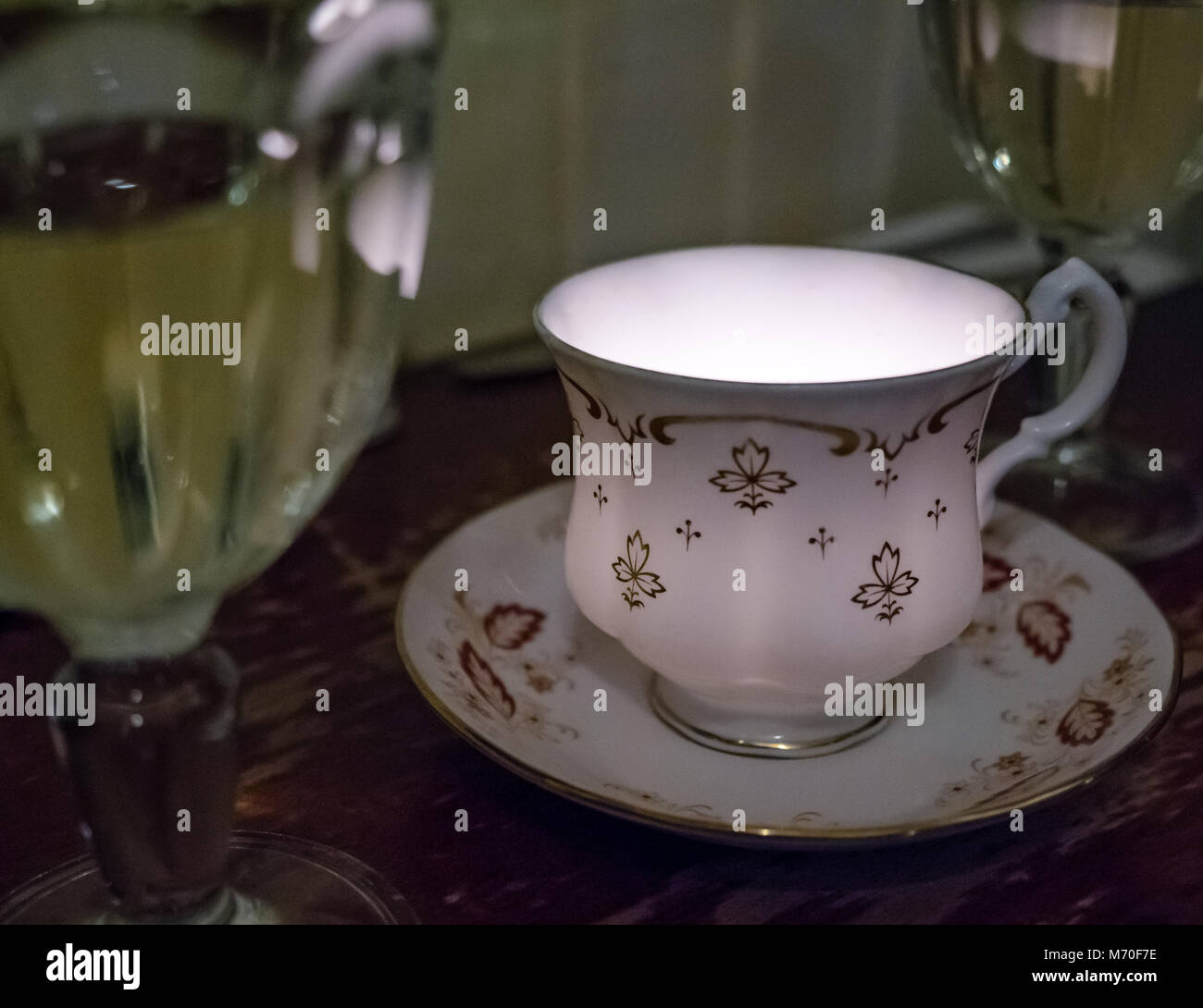 Close up of old fashioned tea cup and saucer with candle light, white wine in glasses, restaurant table, Leith, Edinburgh, Scotland, UK Stock Photo