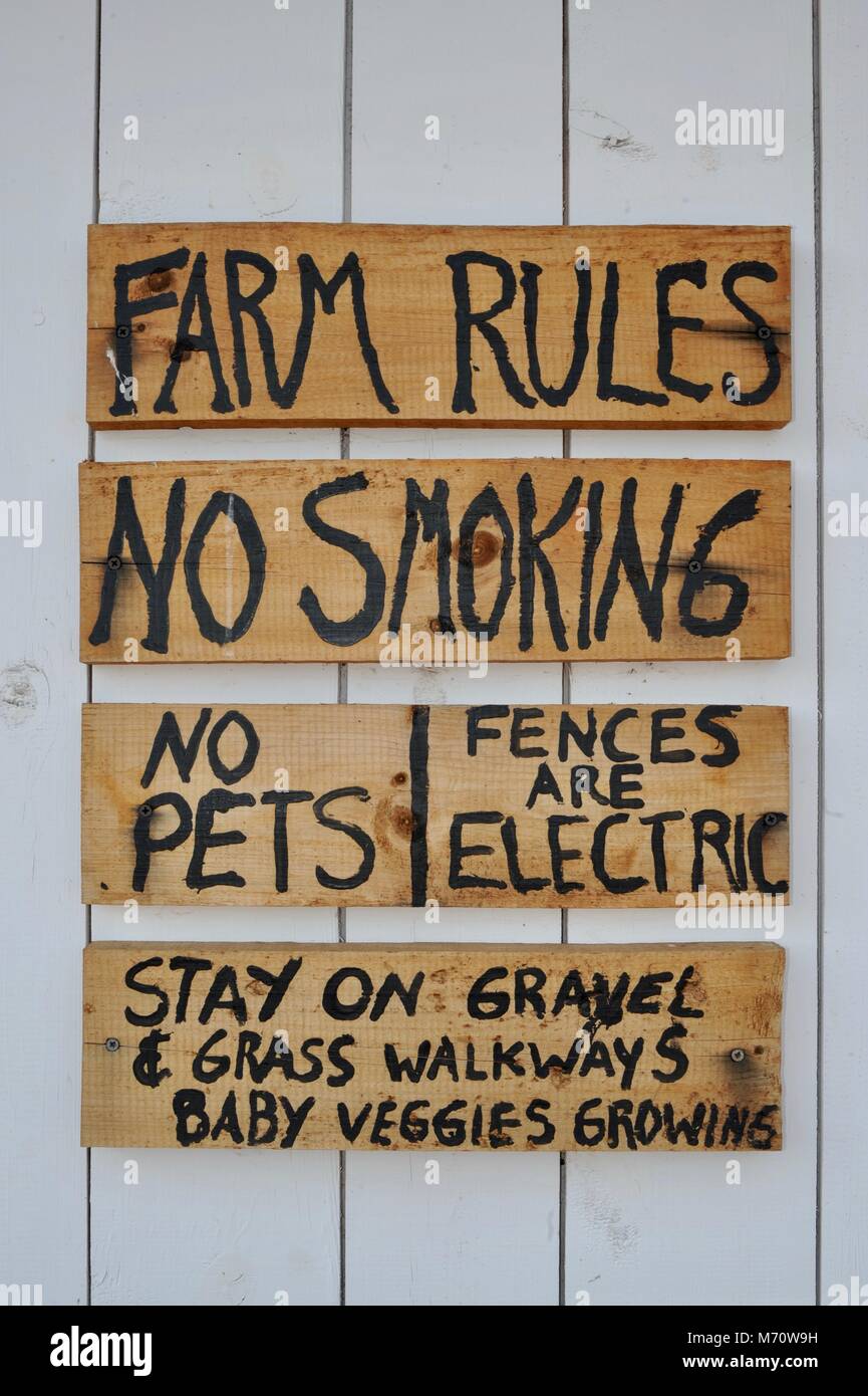 'Farm Rules' hand-lettered wooden sign hanging on side of outbuilding farm barn in Wisconsin, USA. Stock Photo