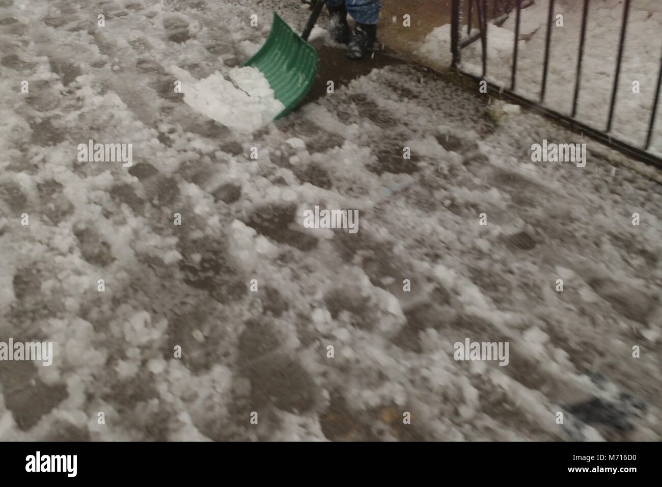 Shoveling a sidewalk covered in slushy snow during the Nor'easter of March 7th, 2018 in Brooklyn New York. Stock Photo