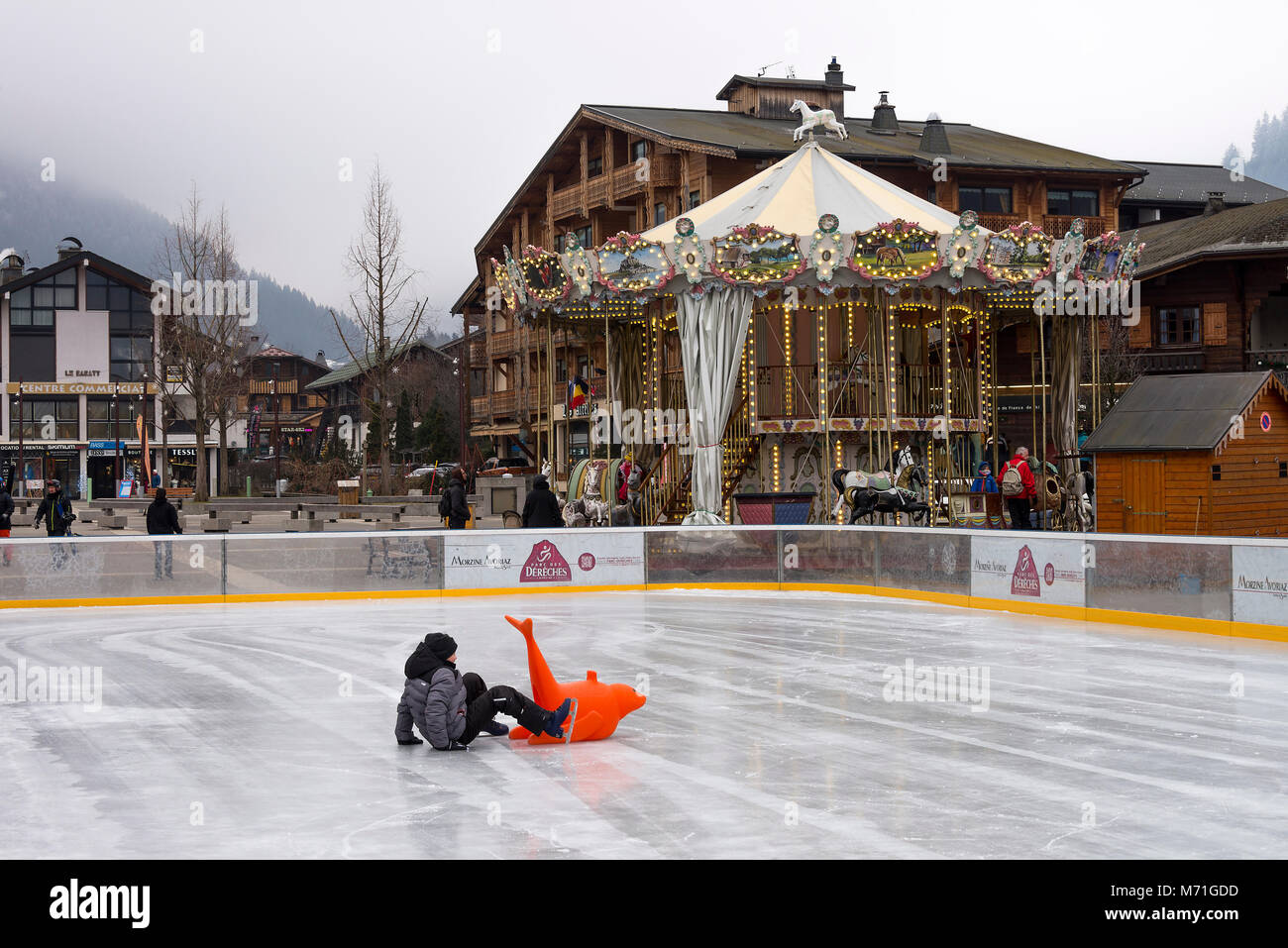 The Outdoor Ice Skating Rink and Carousel Roundabout in the Town Square With Shops in Morzine Haute Savoie Portes du Soleil French Alps France Stock Photo