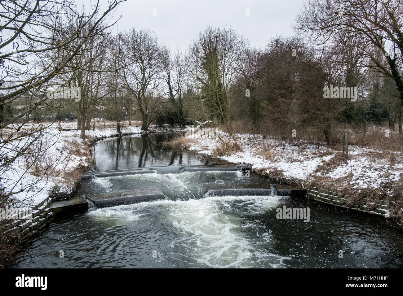 The River Lea tumbles over a flume  after a heavy snowfall in Hertford,UK Stock Photo