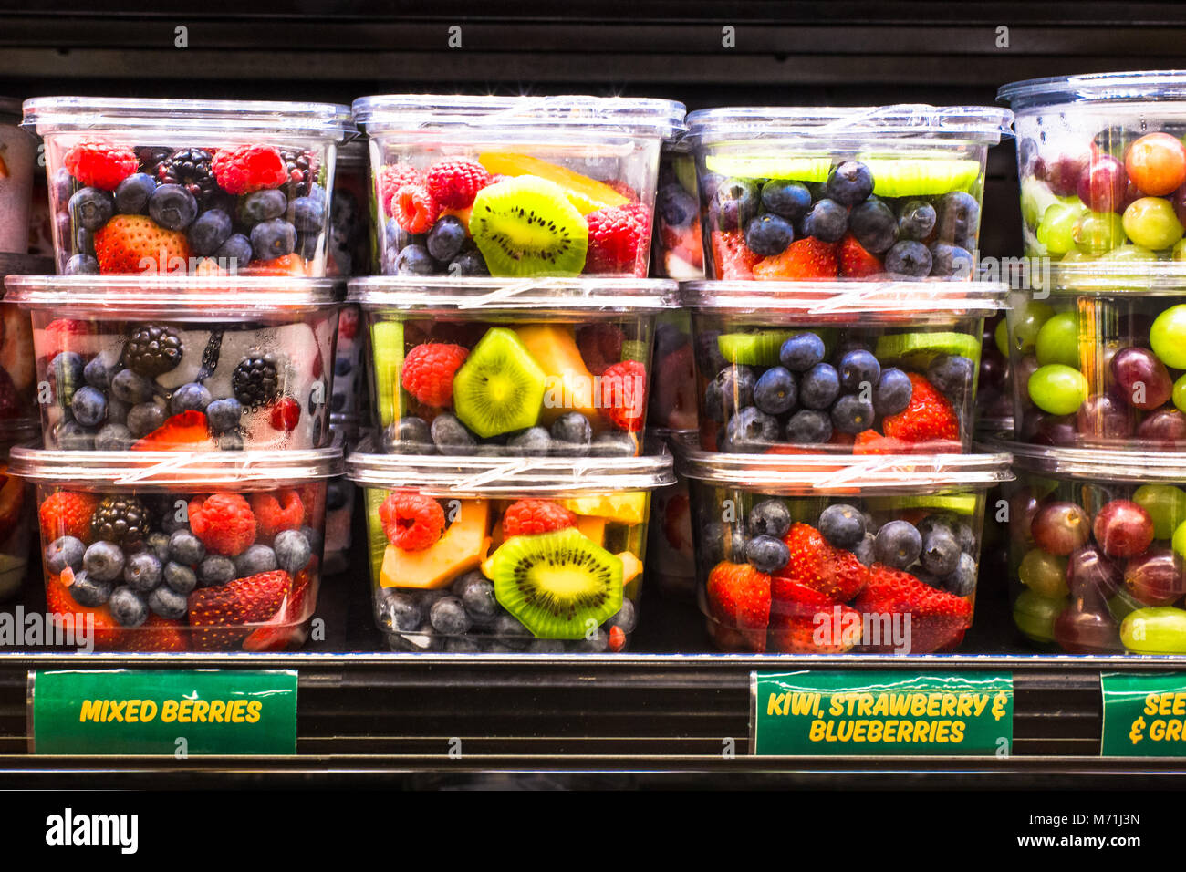 supermarket grocery display case with fresh cut fruit on shelves in