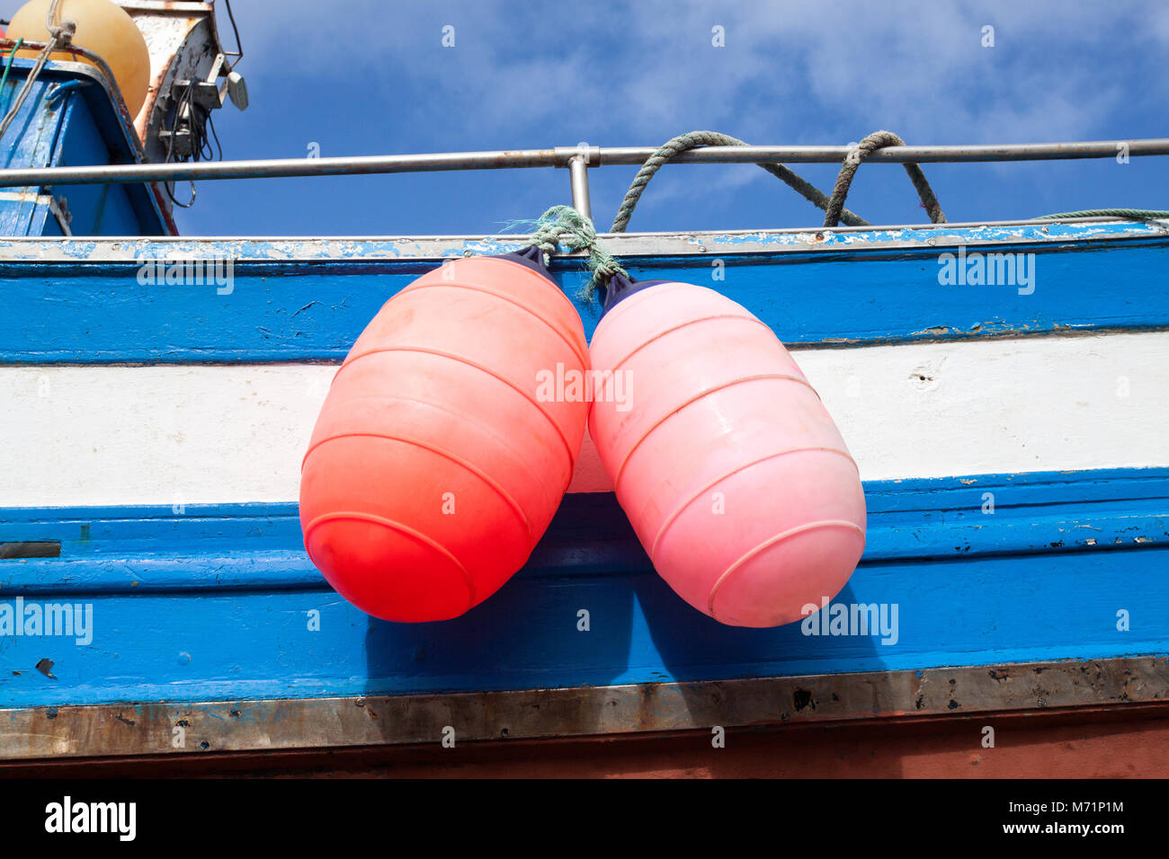 Two bright buoys hanging from the side of a fishing boat on the island