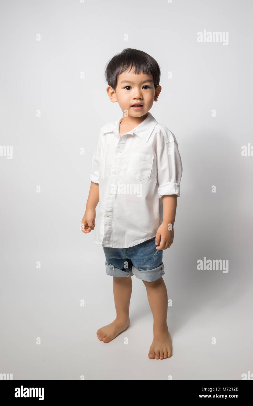 Portrait of 2 years old boy wear white shirt and shorts jean on white background. Stock Photo
