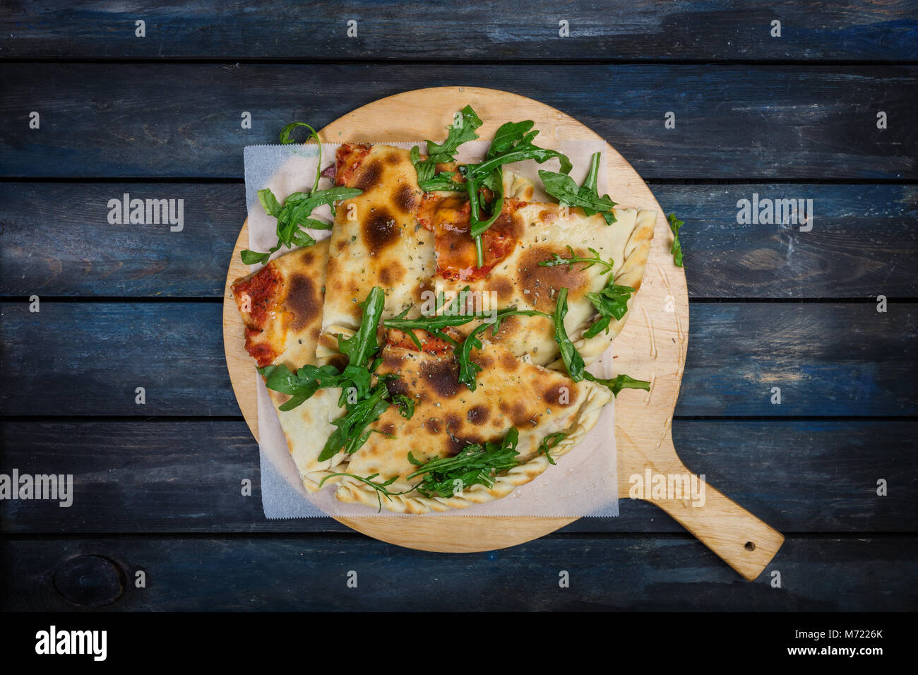Calzone - Stuffed Pizza with ham, mushrooms, arugula and cheese. Stock Photo