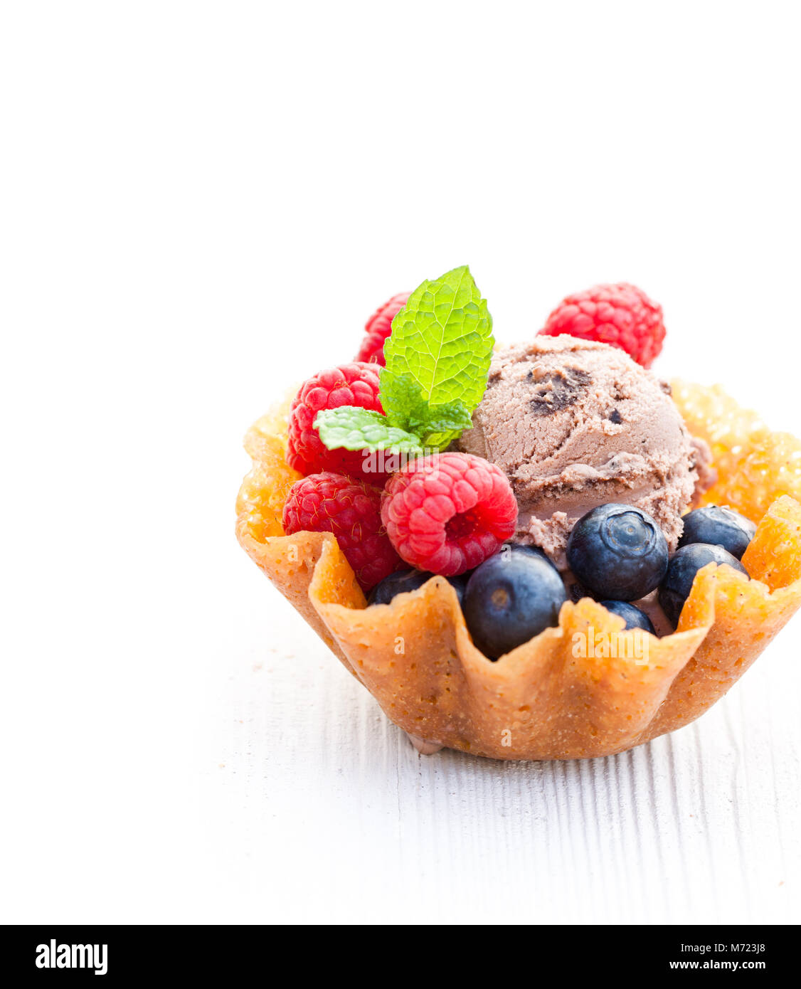 brandy snaps basket with chocolate ice cream and berries on white
