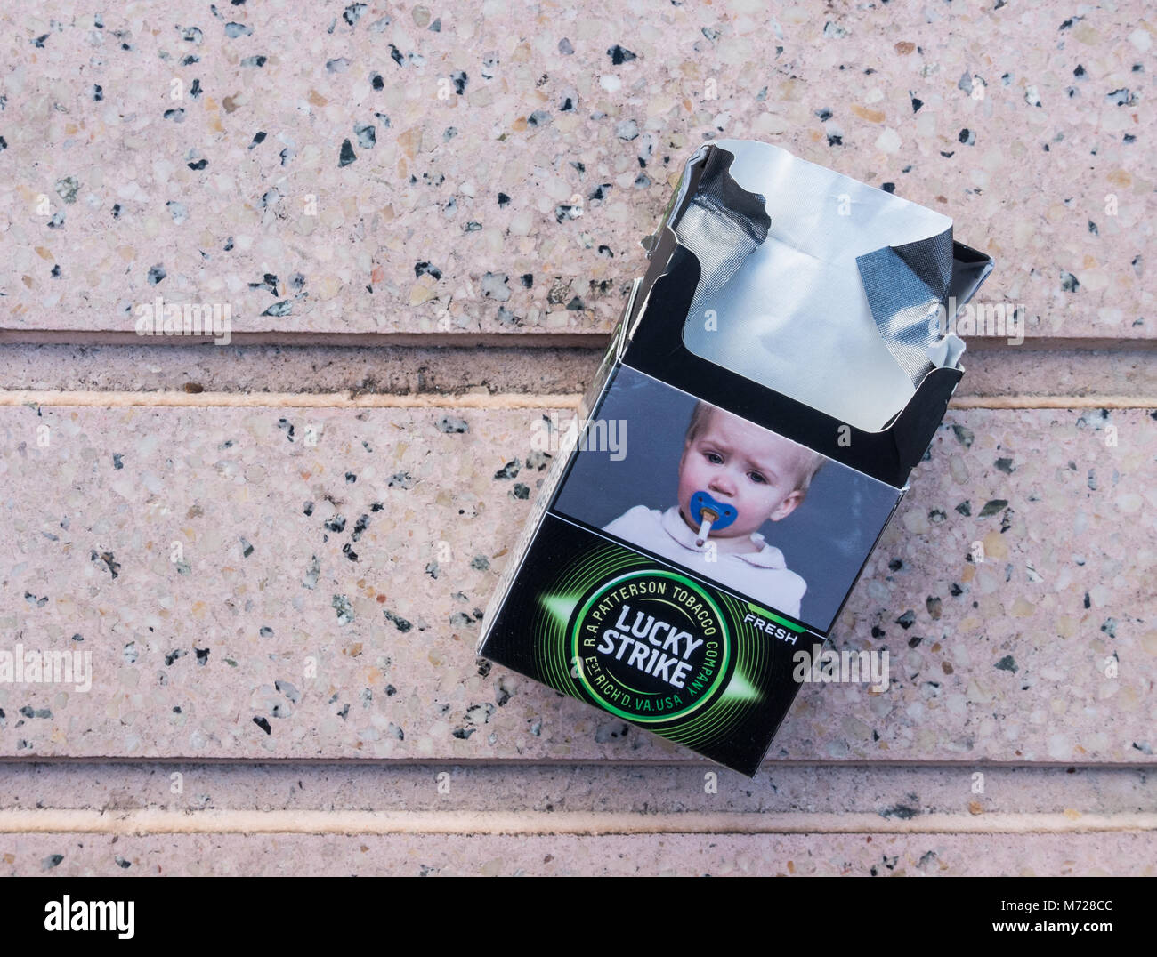 Health warning on discarded cigarette packet in Spain depicting a baby`s dummy with cigarette. Stock Photo