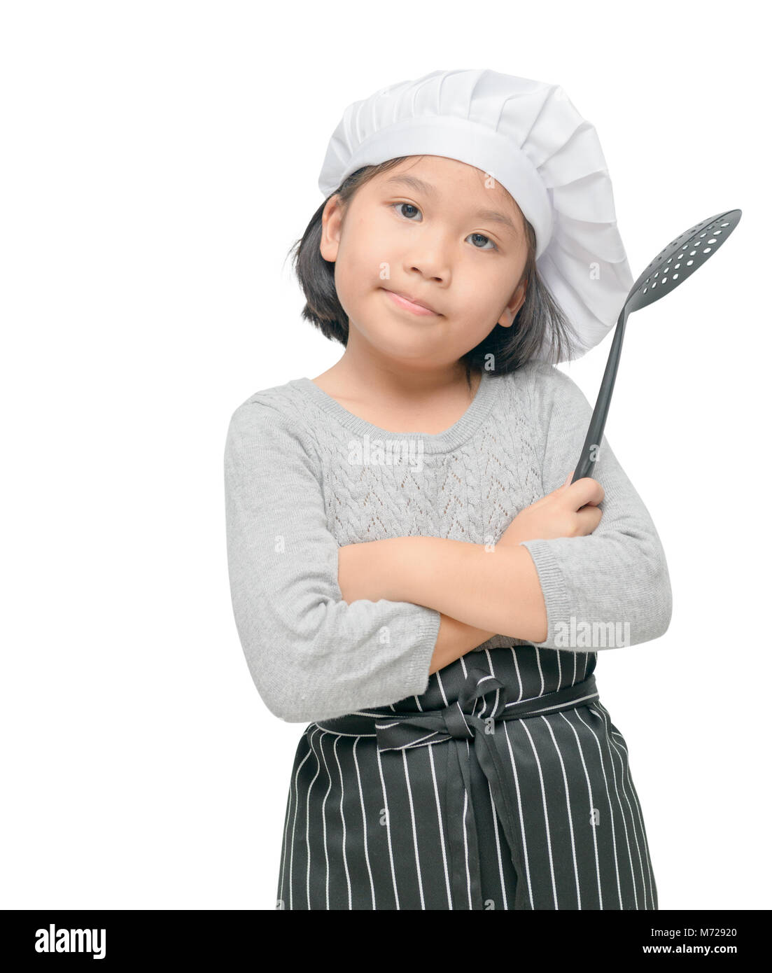 Portrait of cute girl chef hold utensils cooking with cook hat and apron stand and smile isolated on white background Stock Photo