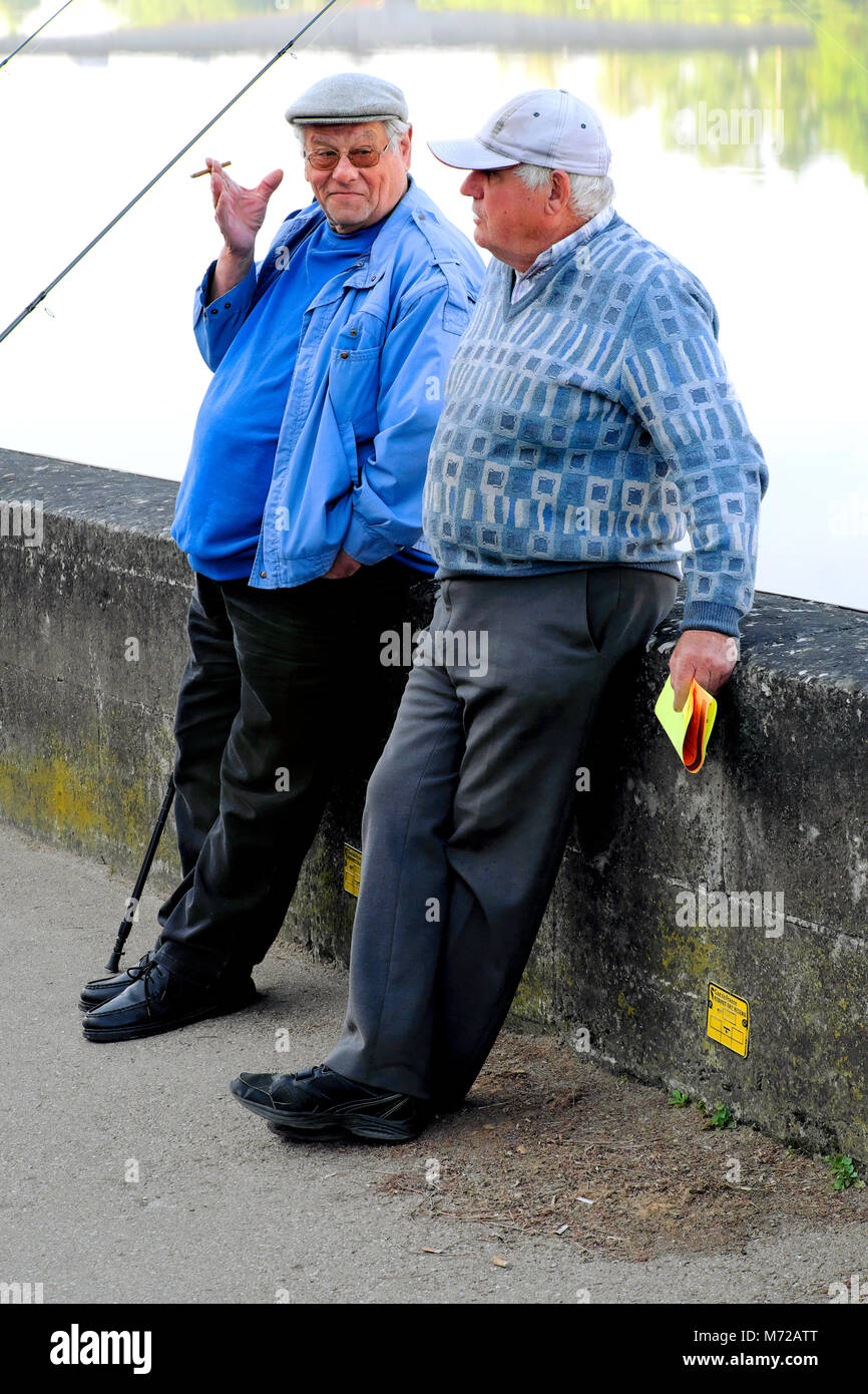 Two elderly men smoke and talk during break from fishing in the Dordogne River, Bergerac, Nouvelle-Aquitaine, France Stock Photo