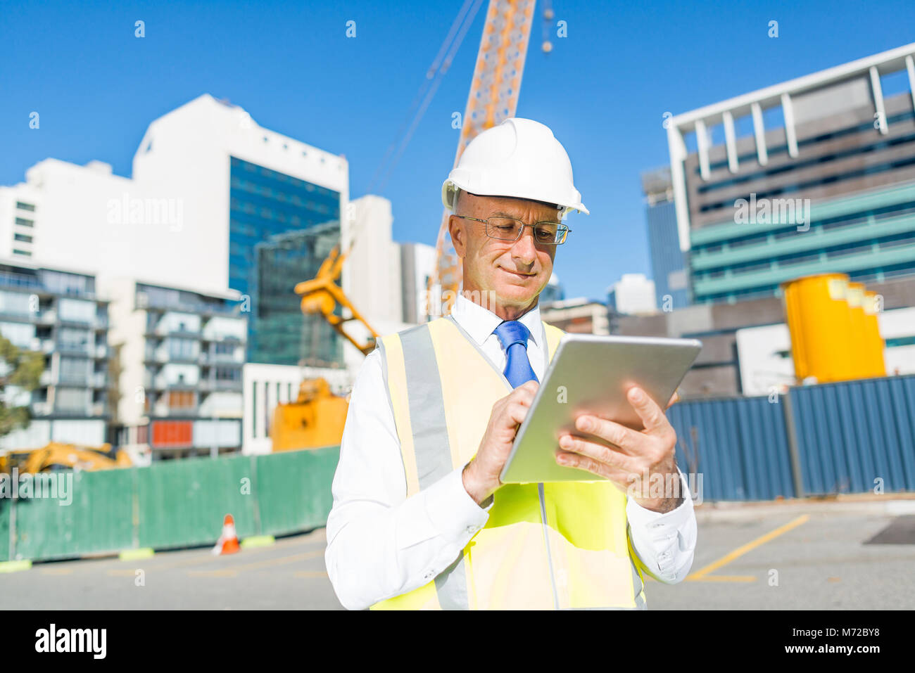Construction manager controlling building site and tablet device in his ...