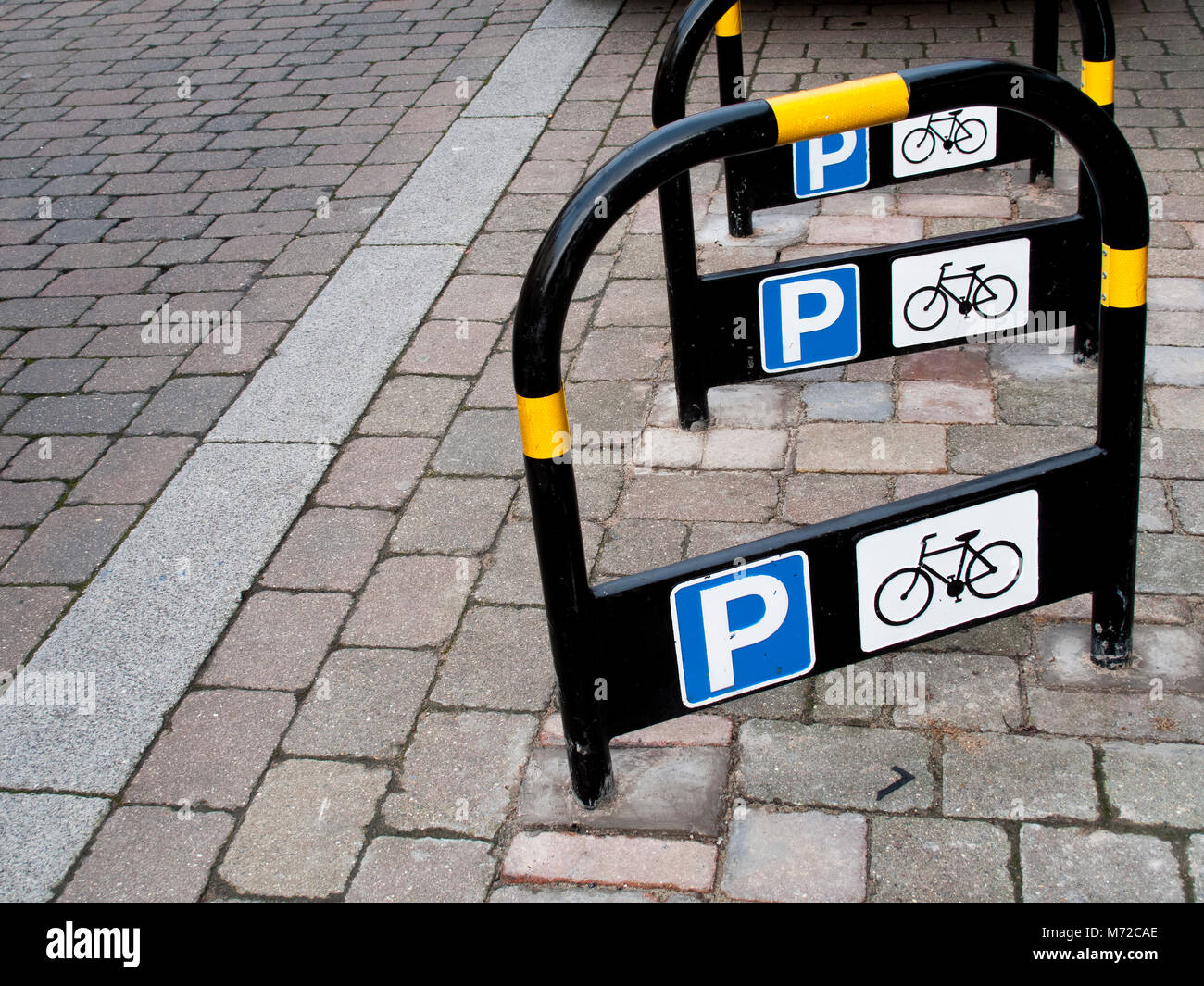 Metal public bicycle parking stands situated on stone paved area of main shopping street Stock Photo
