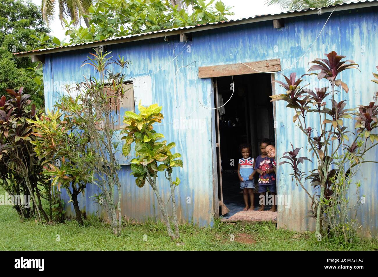 Children pose in the doorway of their simple home constructed of corrugated iron in a village outside Nadi. Stock Photo