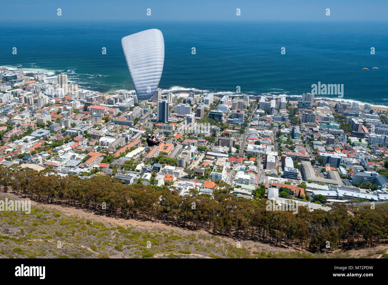 Tandem paraglider flying above Cape Town’s Atlantic seaboard suburbs. Stock Photo
