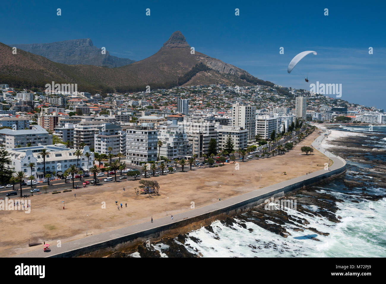 Tandem paraglider flying above Cape Town’s Atlantic seaboard suburb of Sea Point with Table Mountain and Lion’s Head in the background. Stock Photo