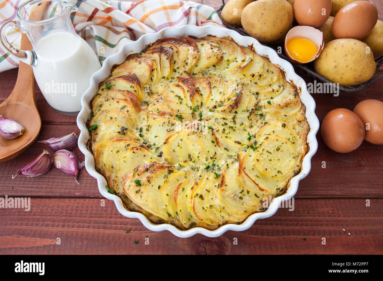 Potato gratin in round baking dish with fresh cooking ingredients Stock