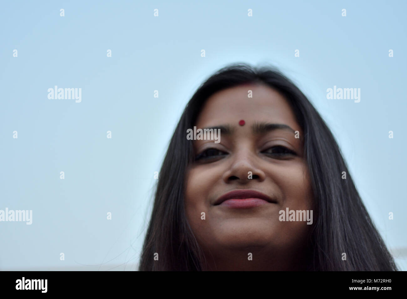 A beautiful bengali lady with long hair is looking straight with a smile. Stock Photo