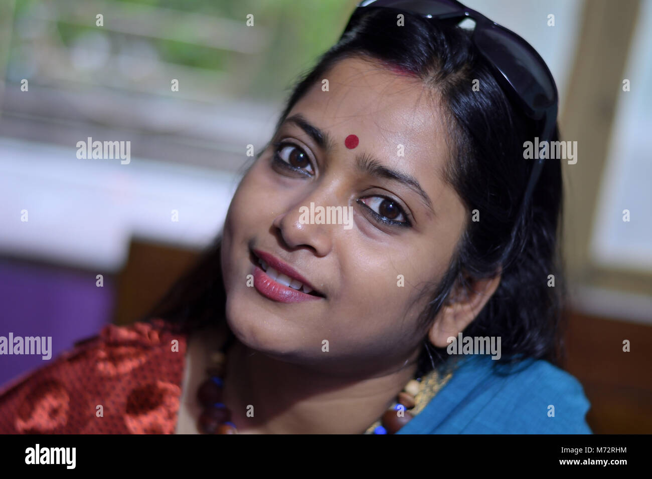 beautiful bengali lady is looking straight with a smile inside the room. Stock Photo