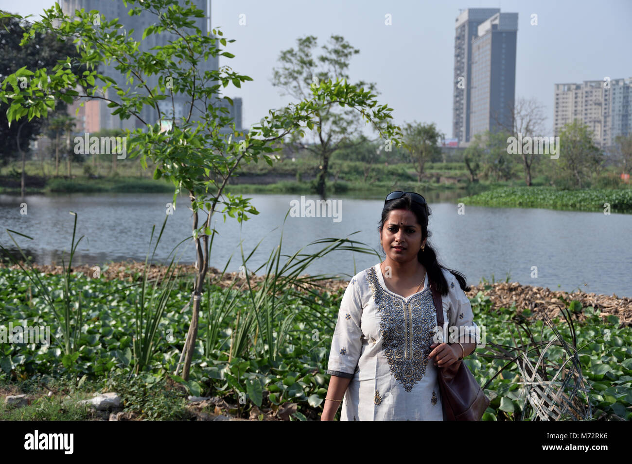 beautiful bengali lady is standing in front of a lake. Stock Photo