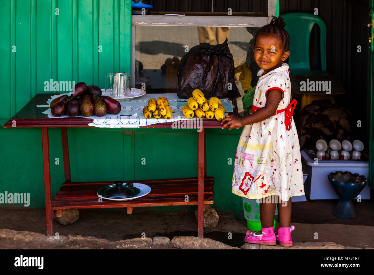 A Little Girl Stands Outside A Shop Selling Fruit, Arba Minch, Gamo Gofa Zone, Ethiopia Stock Photo